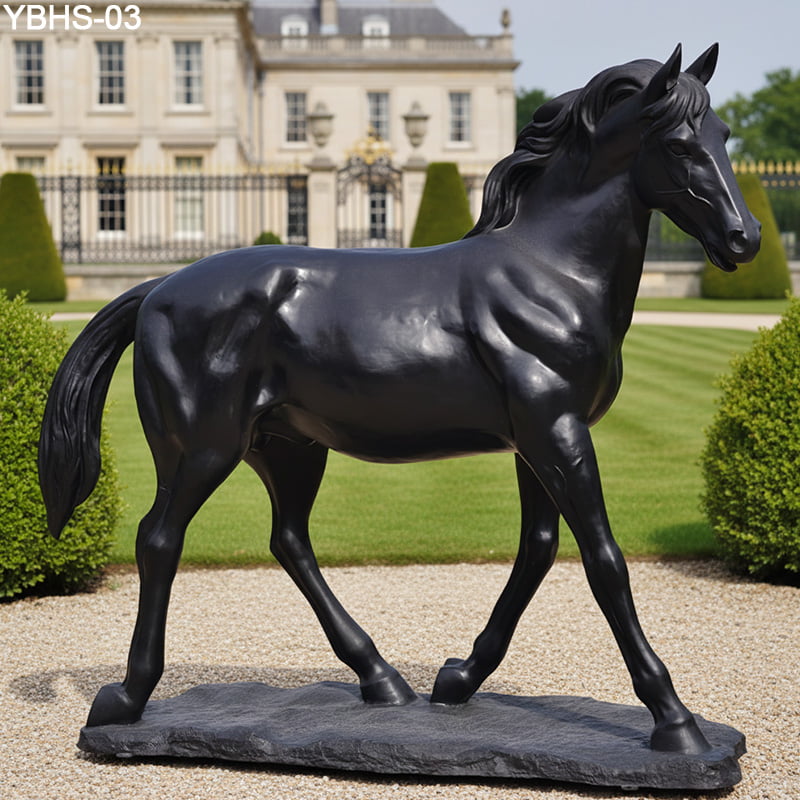 Detailed black bronze horse statue on a stone base, situated in a formal garden outside a historic castle with trimmed lawns and hedges.
