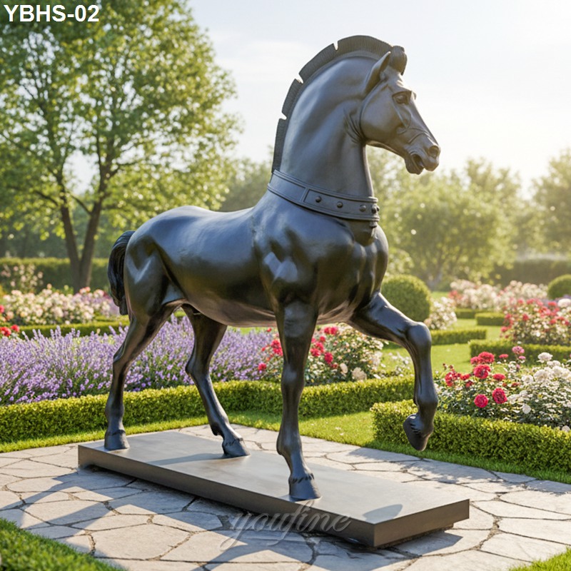 A sleek bronze horse sculpture stands on a stone base surrounded by vibrant flowers and neatly maintained garden landscaping