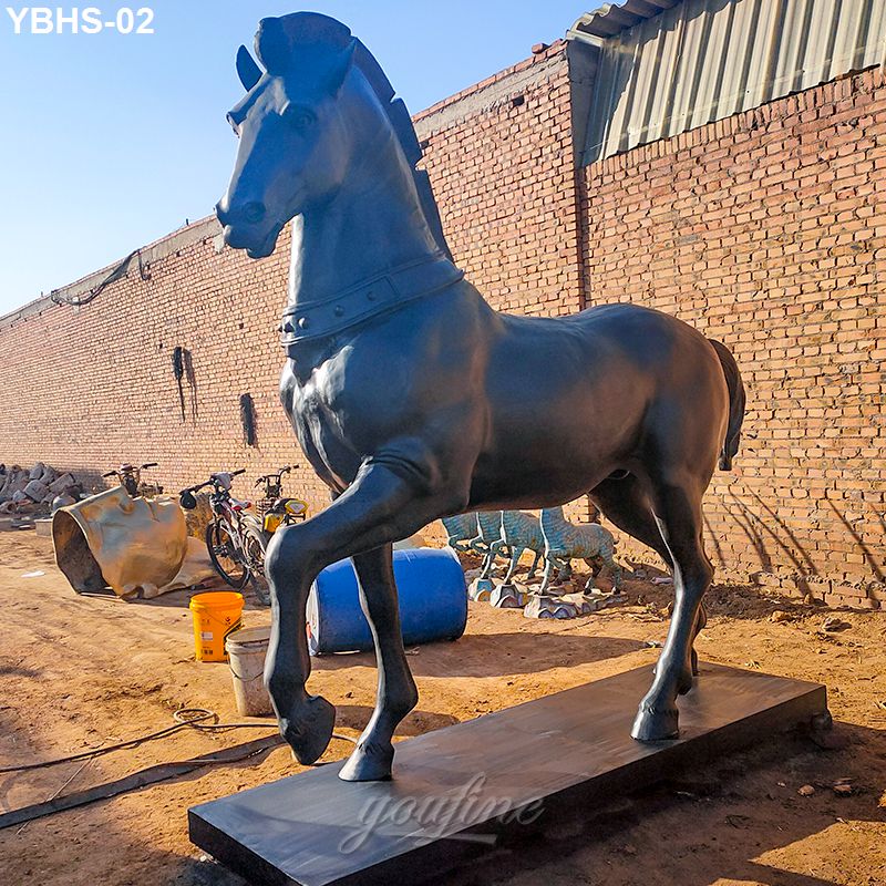 A detailed bronze horse sculpture with raised front leg displayed outdoors