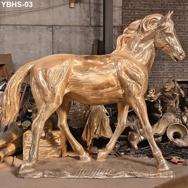 A golden bronze horse sculpture with intricate details displayed in an artisan workshop surrounded by other artistic creations.