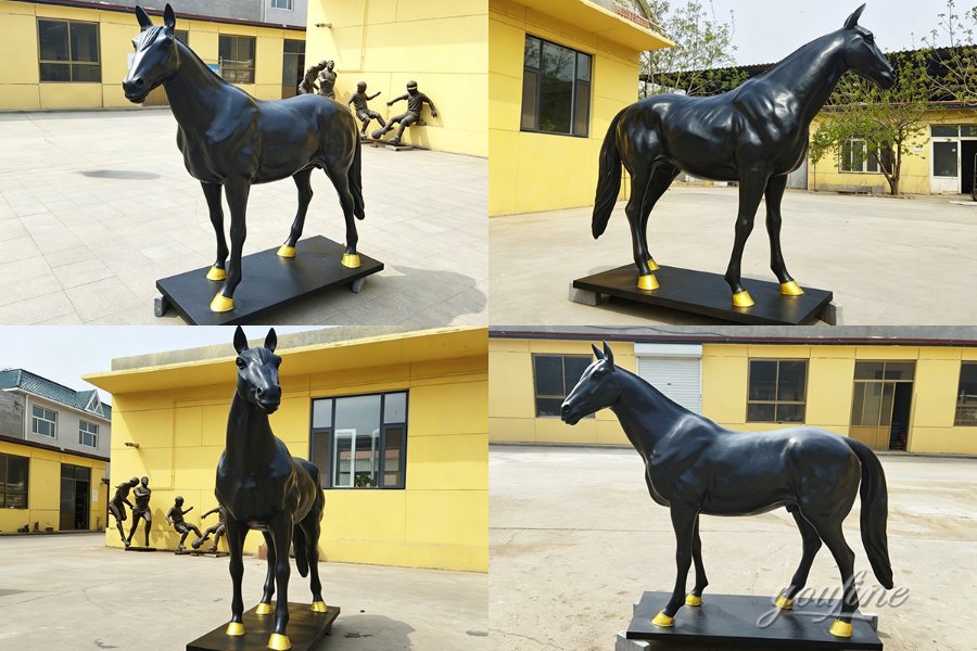 Black bronze horse statue standing on a rectangular platform with gold-painted hooves, displayed in an outdoor area with yellow buildings.