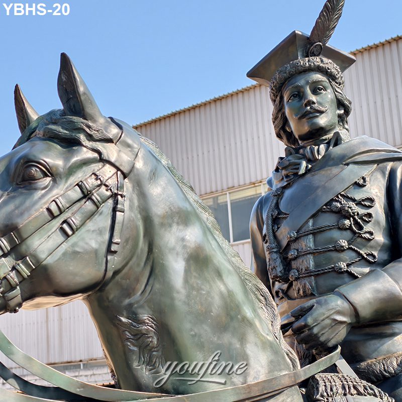Close-up of a detailed bronze equestrian statue featuring a rider in historic military attire with feathered hat and a bridled horse.