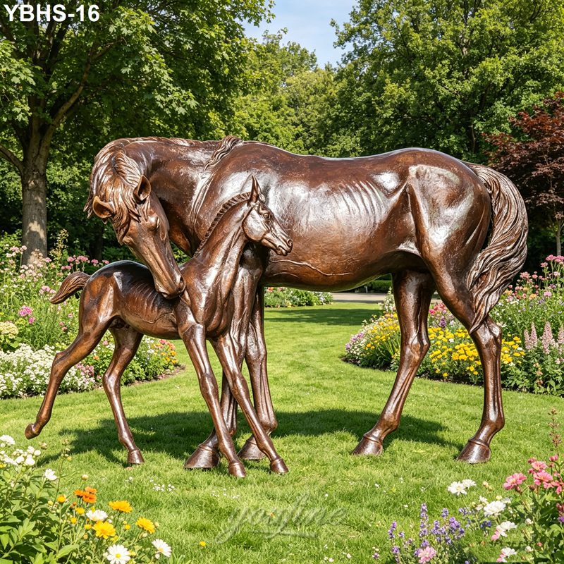 Elegant bronze horse and foal sculpture surrounded by colorful flowers and greenery in a landscaped garden during daylight.