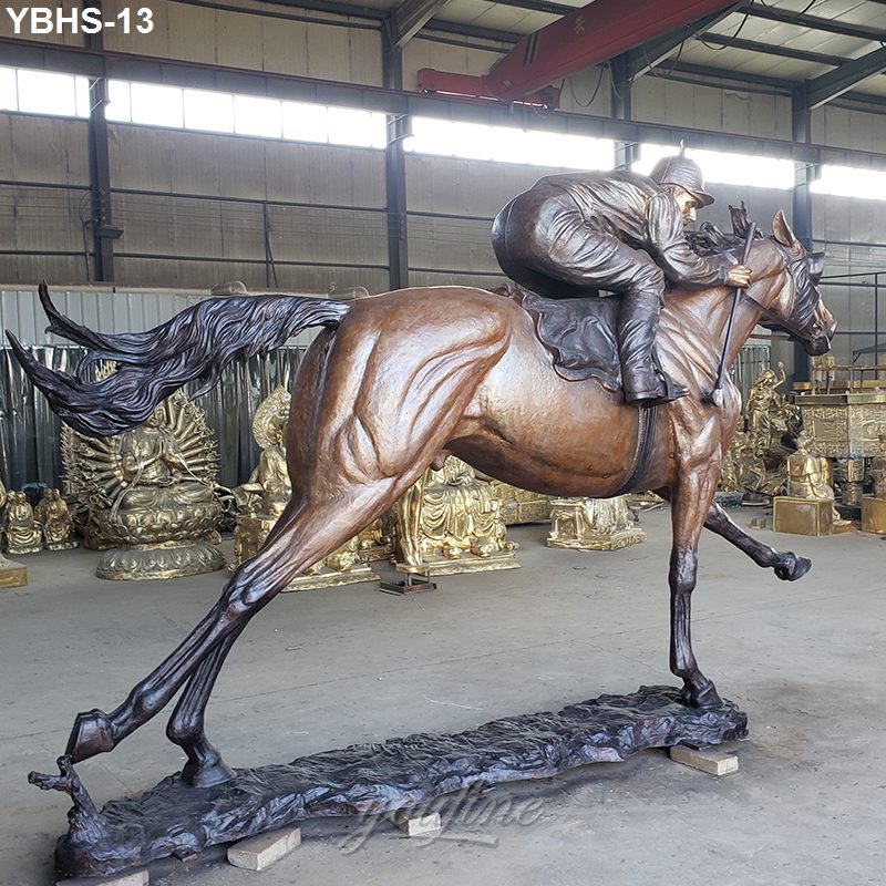 Bronze sculpture of a galloping horse with a jockey in full gear, displayed inside a workshop with other statues in the background.