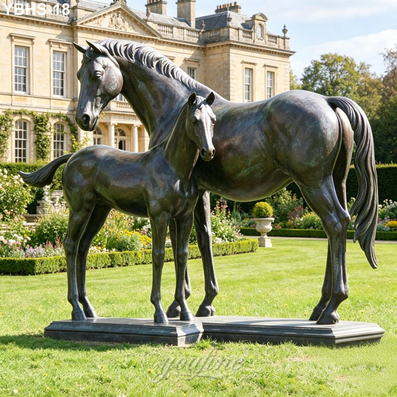 Bronze sculpture of a horse mare and foal placed on a lush green lawn with an elegant castle backdrop. A symbol of strength and heritage.