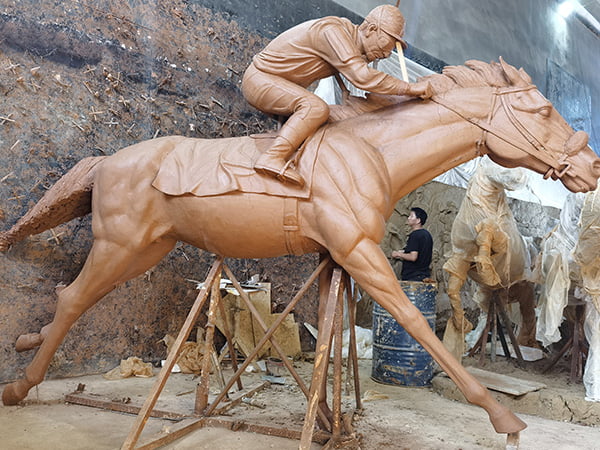 Master sculptor hand-building clay model of rearing bronze horse