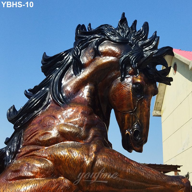 Detailed close-up of a bronze horse sculpture with flowing mane, muscular body, and lifelike expression against a clear sky.