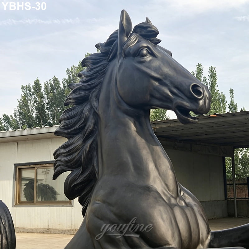 Close-up of a bronze horse sculpture showcasing a muscular form, flowing mane, and expressive face in an outdoor setting.