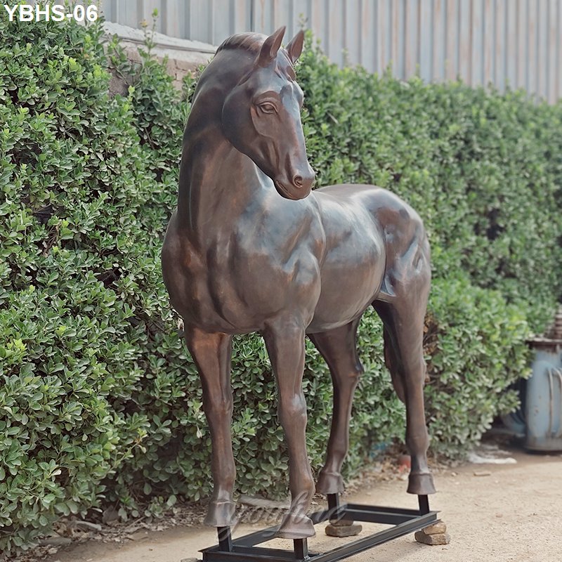 Elegant bronze horse sculpture with lifelike detailing, displayed outdoors on a metal stand, surrounded by lush greenery.