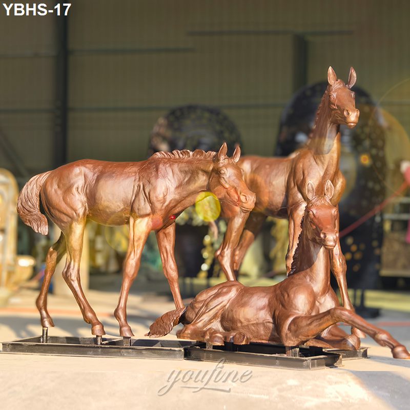 Three finely crafted bronze horse sculptures depicting young foals in lifelike postures, set indoors with warm lighting.