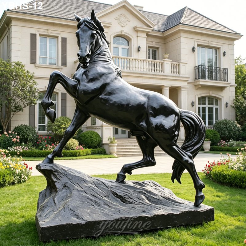A large, detailed bronze horse sculpture with a rearing pose on a stone base, displayed in the manicured garden of a luxurious estate.