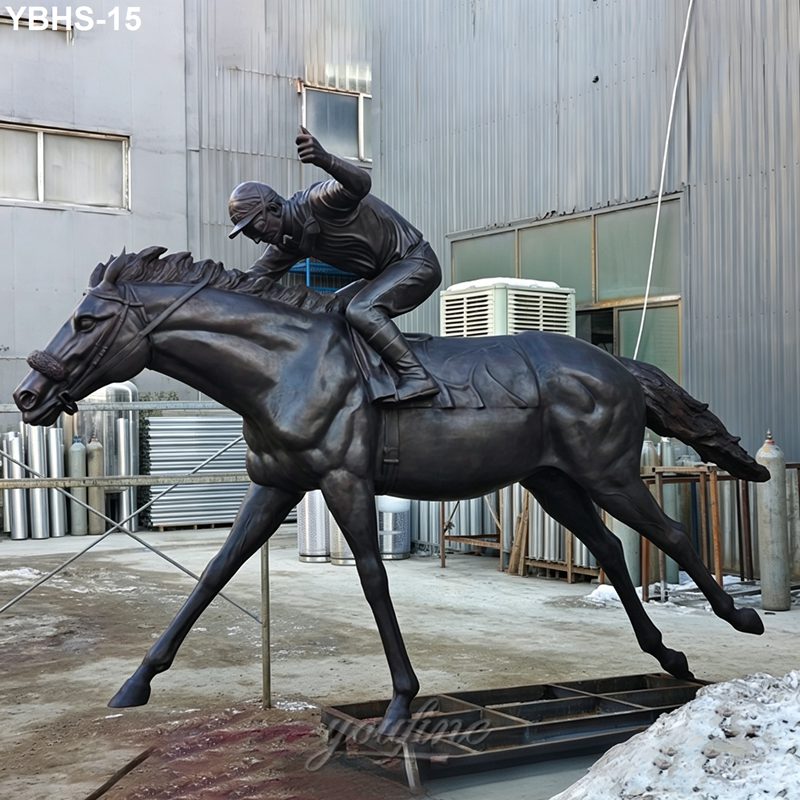 A lifelike bronze statue depicting a jockey riding a galloping horse, mounted outdoors amidst industrial surroundings.