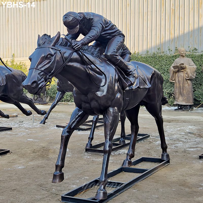 Lifelike bronze statue of a jockey riding a horse in racing pose, set outdoors with other sculptures visible nearby.