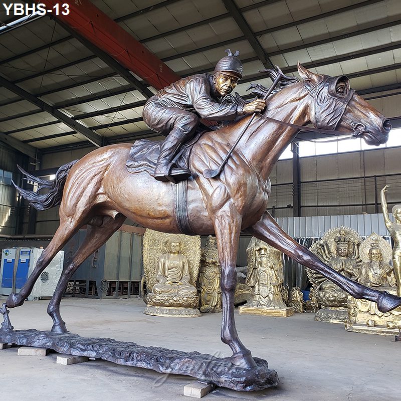 Detailed bronze statue of a jockey riding a racehorse, displayed indoors in a workshop surrounded by golden sculptures.