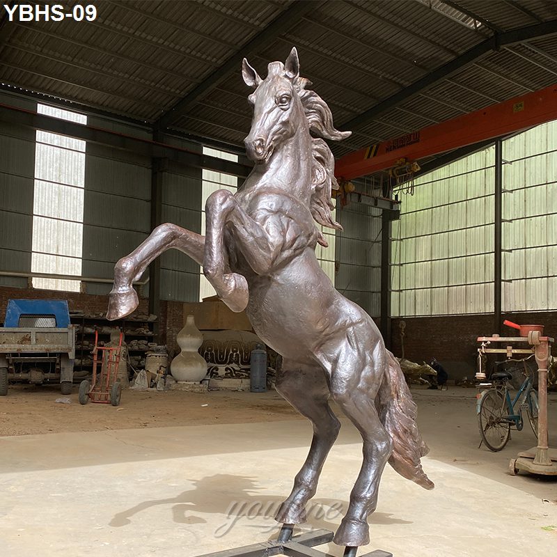 Detailed bronze sculpture of a rearing horse displayed in an industrial workshop setting, showing its strength and craftsmanship.