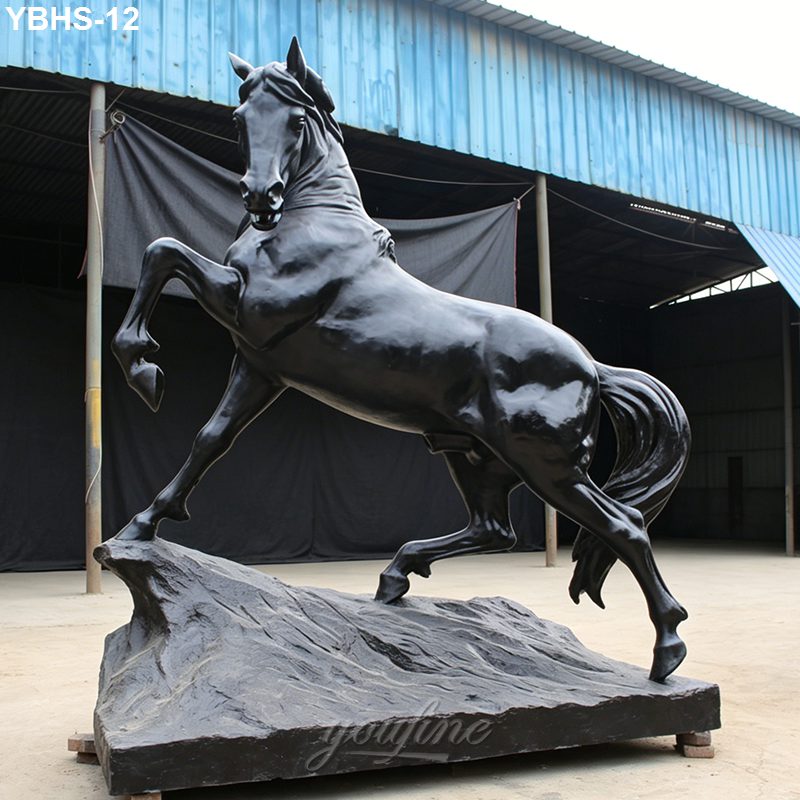 Bronze horse sculpture in a rearing pose stands on a detailed rocky base, showcasing strength and elegance in an outdoor space.