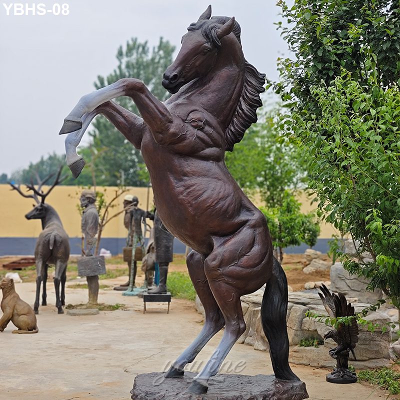 A bronze horse statue in a dynamic rearing pose, surrounded by trees and other sculptures in an outdoor display area.