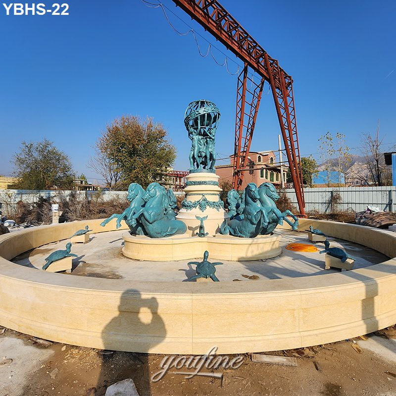 Large circular fountain featuring detailed bronze statues, including figures, turtles, and central globe sculpture, in bright outdoor setting.