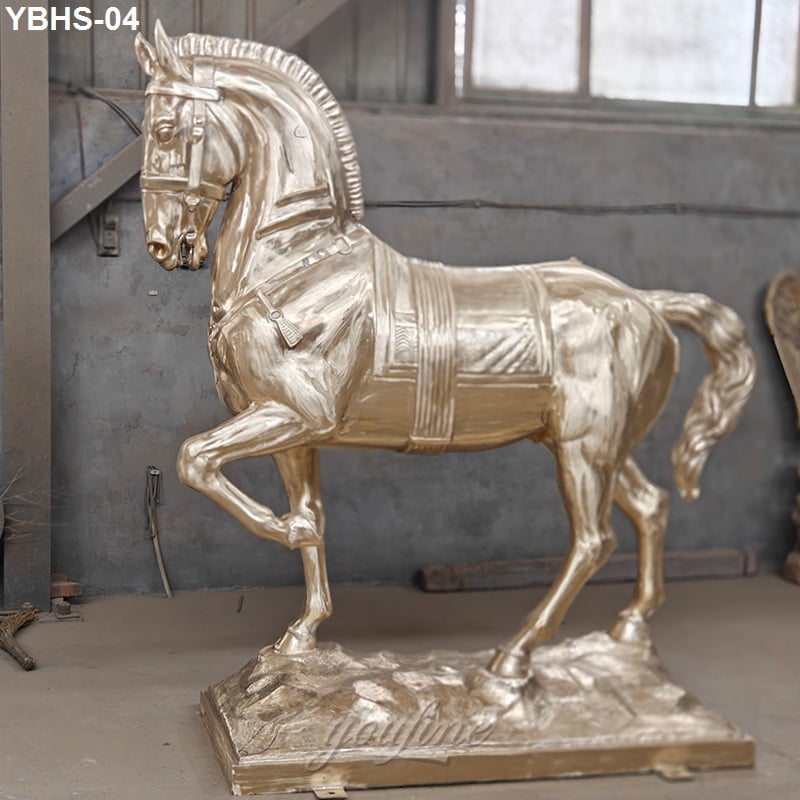 An unfinished bronze horse sculpture, situated within a workshop setting, stands atop a textured pedestal.
