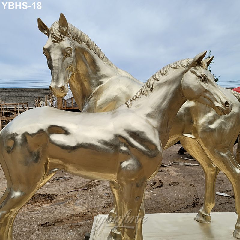 Two golden bronze horse sculptures with intricate details, showcased outdoors against a cloudy sky. Ideal for estates or equestrian properties.