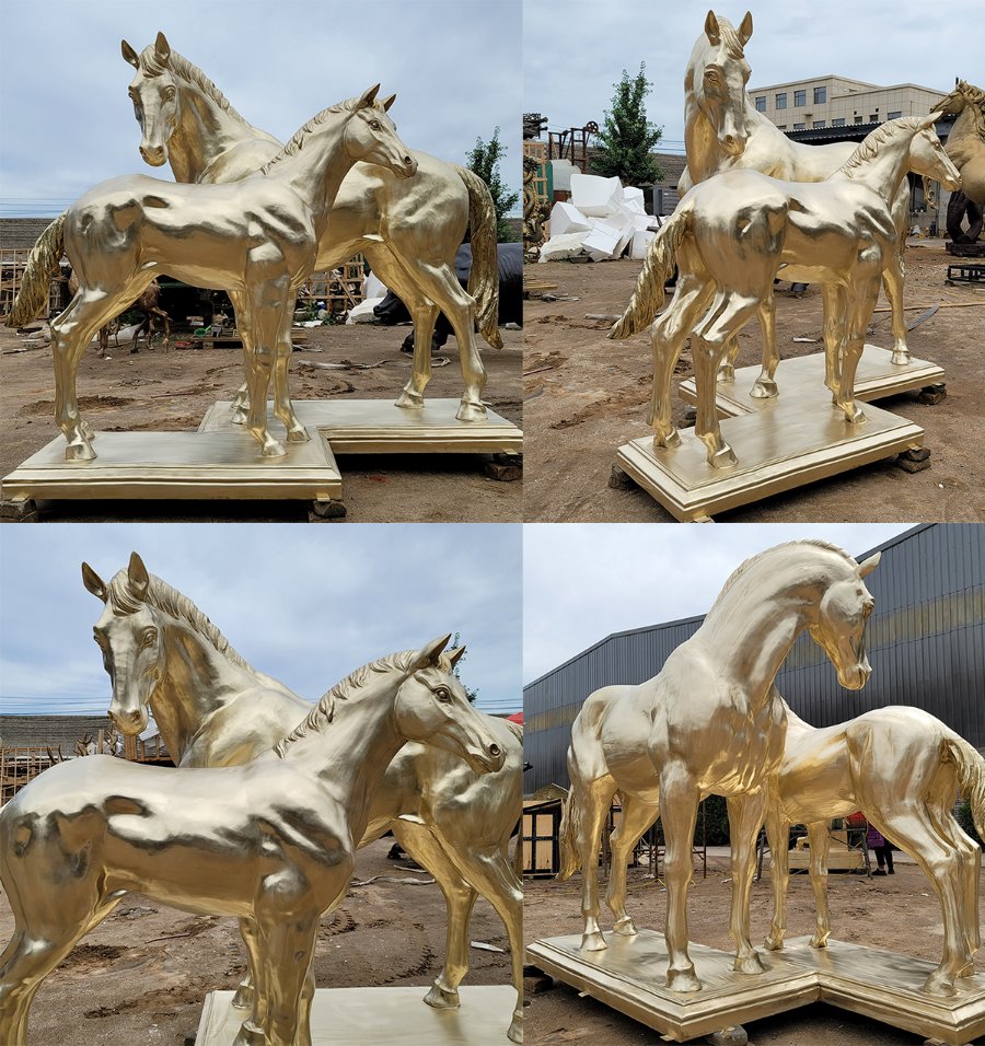Golden bronze horse sculptures depicting two horses standing on bases in an outdoor setting. Detailed craftsmanship and polished surfaces.