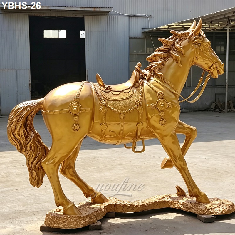 Golden bronze horse statue featuring intricate saddle and decorative design, standing on detailed base with outdoor industrial background.