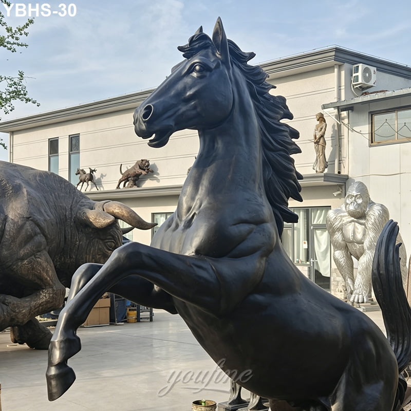 Large rearing bronze horse sculpture with lifelike details displayed outdoors alongside other statues, including a buffalo and gorilla.