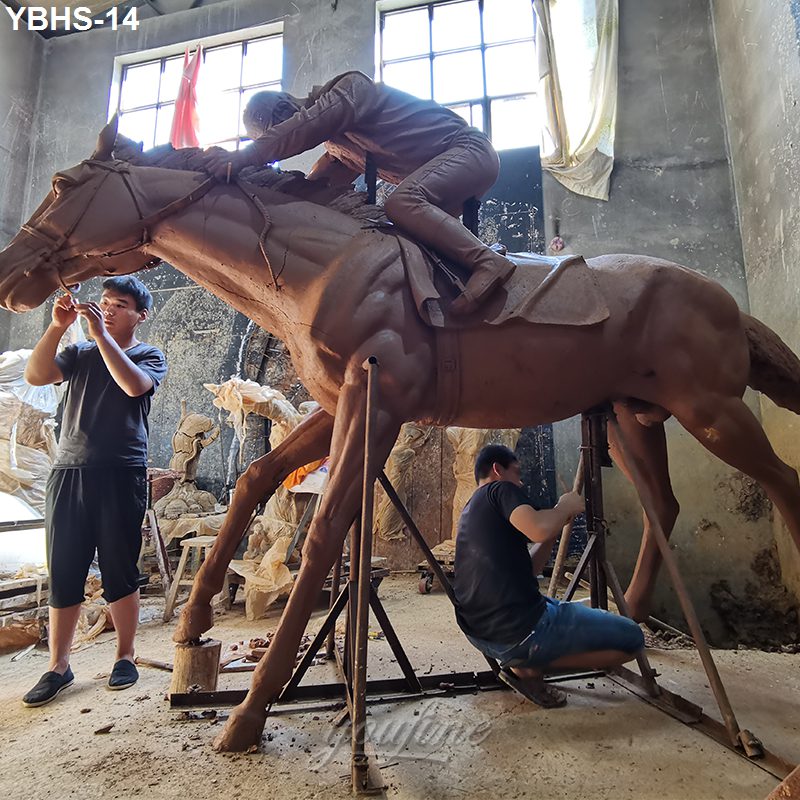 Sculptors shaping a life-sized clay model of a horse with a rider in a workshop, preparing for bronze casting.