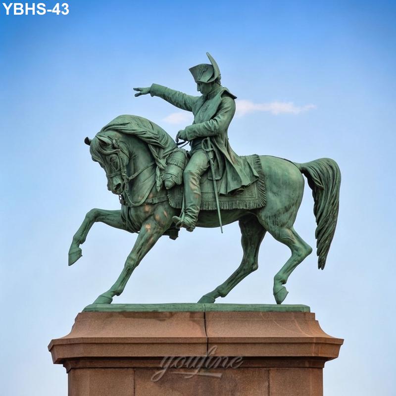 A bronze equestrian statue featuring a rider pointing forward, mounted on a rearing horse, set against a clear blue sky.