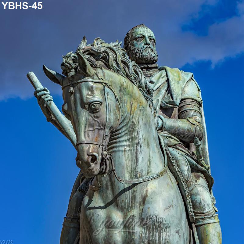 A bronze equestrian statue featuring a clad rider holding a baton, mounted on a detailed horse, set against a clear blue sky.