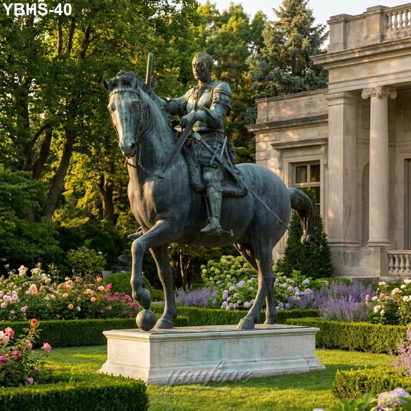 Bronze statue of an armored knight on horseback on a stone pedestal, set in a manicured garden with flowers and greenery near a classical building.