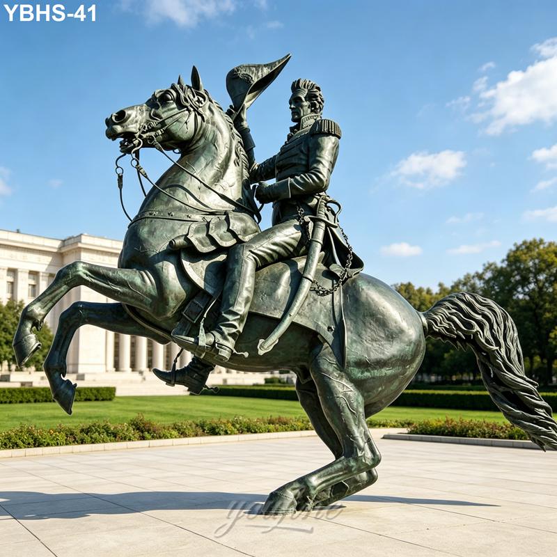 Bronze statue of a figure on a rearing horse, set on a plaza with manicured greenery and a historic-style building in the background.