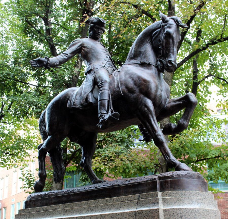 Bronze equestrian statue of a historical figure on a rearing horse, placed on a stone pedestal amidst trees in a public park.