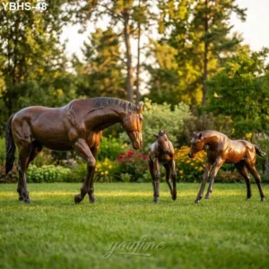 Bronze sculptures of a horse with two foals displayed outdoors in a lush garden, symbolizing elegance and heritage.