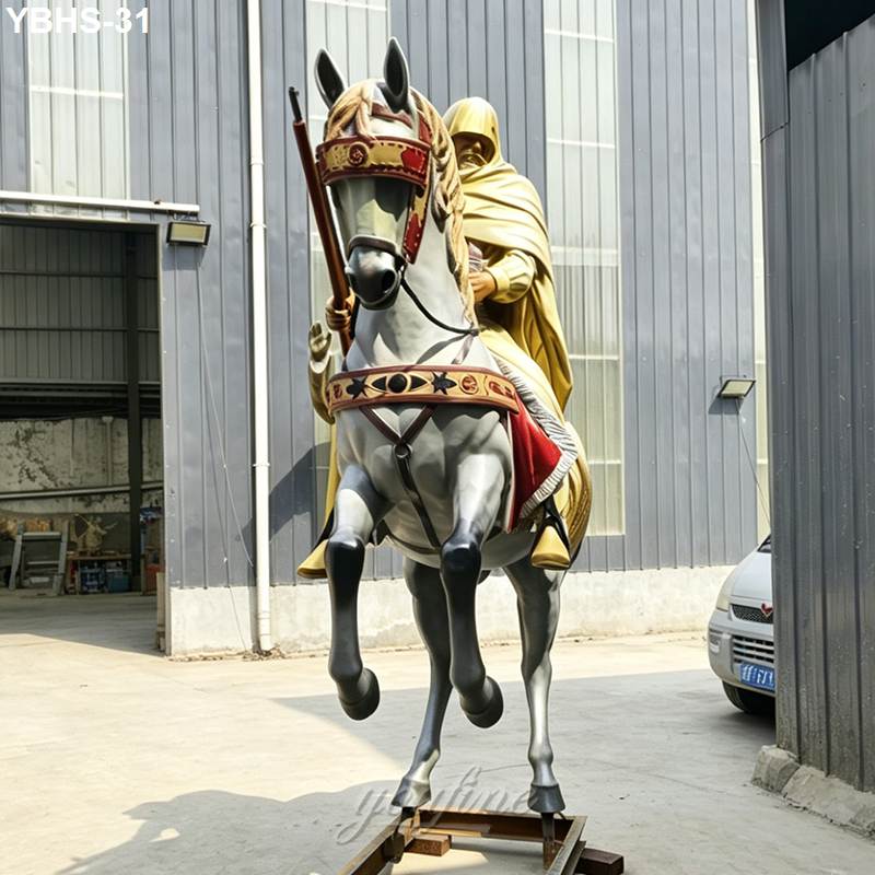 A bronze sculpture of a rider on a horse, featuring intricate decorative details, displayed outdoors in an industrial setting.