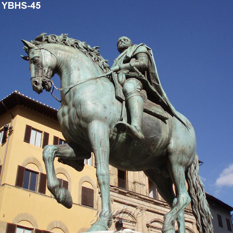 A striking bronze sculpture of a rider atop a rearing horse with intricate detailing, set against a clear blue sky and buildings in the background.