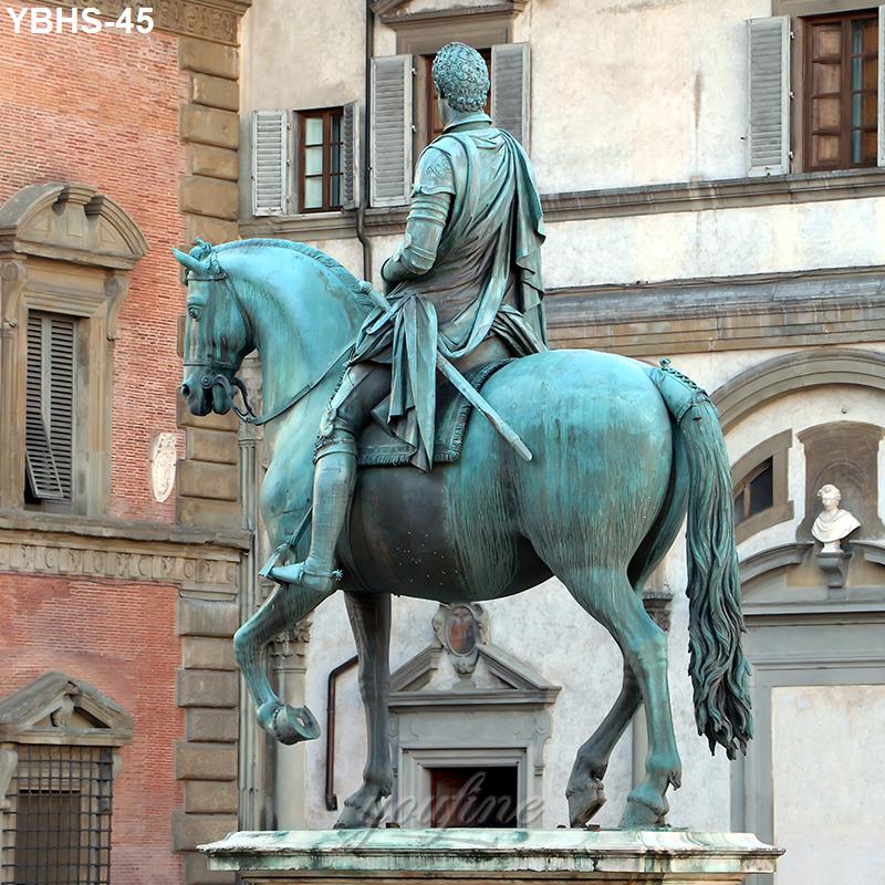 A detailed bronze equestrian statue depicting a rider on horseback in front of historic architectural facades in a plaza setting.