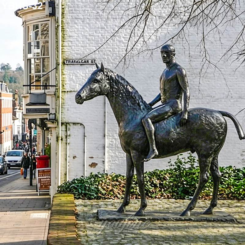 A bronze statue of a rider on a horse, set on a pedestal in a cobblestone town square with historic buildings in the background.