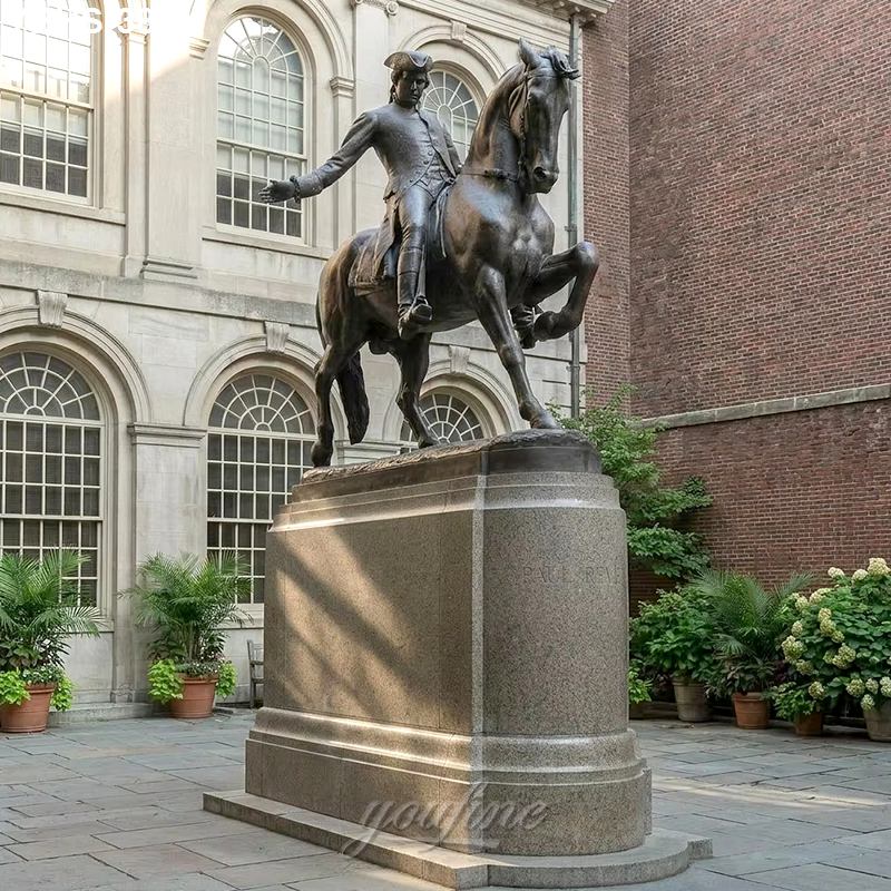A bronze equestrian statue depicts a figure riding a horse with one hoof raised, set on a stone pedestal in a courtyard with arched windows and greenery.
