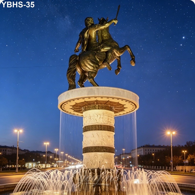 A bronze statue of a horseman holding a sword, mounted on a decorative fountain with flowing water, illuminated under a starry night sky.
