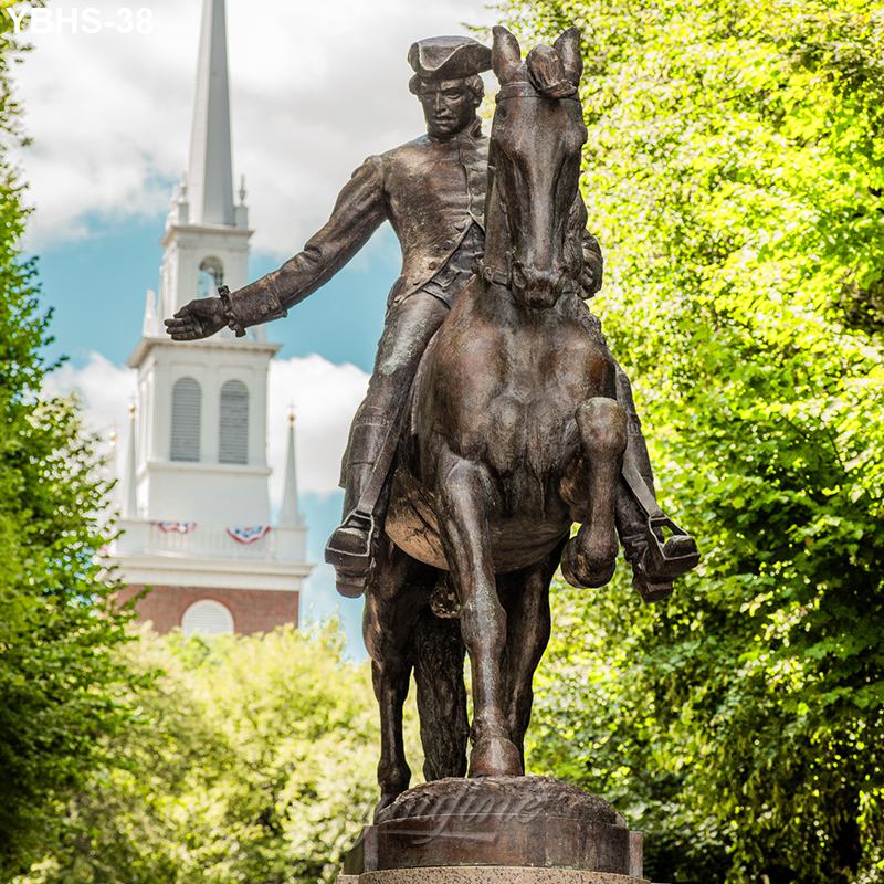 Bronze equestrian statue of a rider on horseback in front of a historic church with a tall steeple, surrounded by trees and a bright sky.