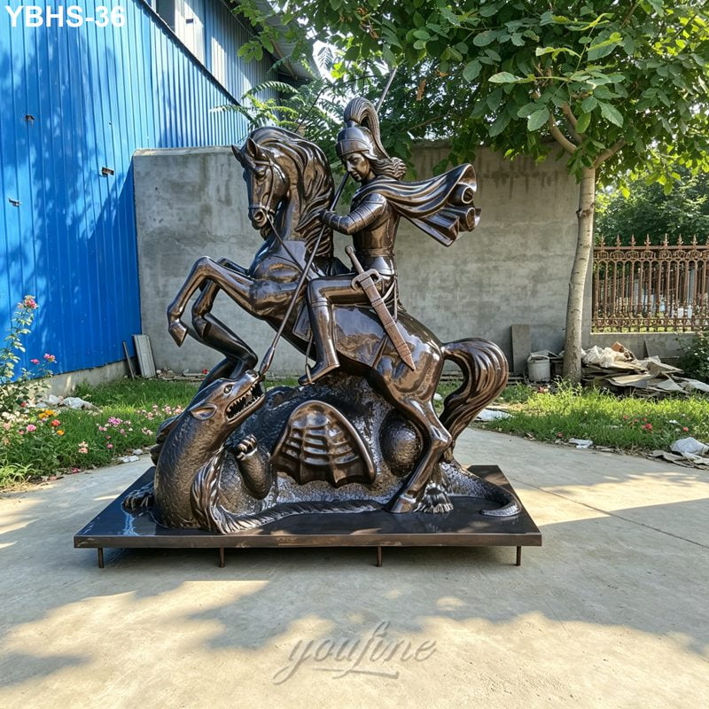 A detailed bronze sculpture depicting a knight on horseback slaying a dragon, placed outdoors near a blue building and trees.