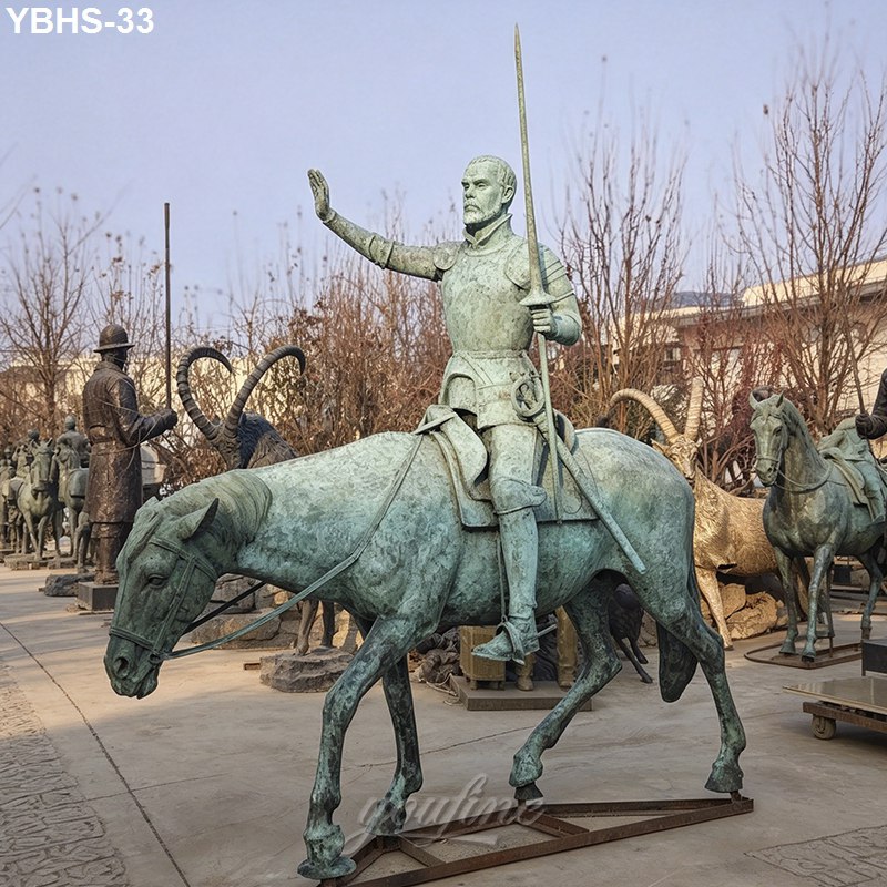 Bronze statue of a knight in armor holding a spear while on horseback, displayed outdoors with other sculptures in the background.