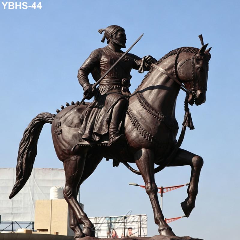 Bronze statue of a warrior on horseback holding a sword, featuring intricate detailing with a blue sky background.