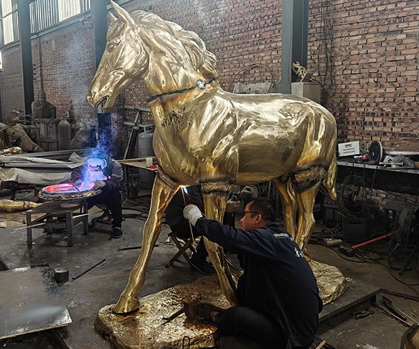 Metal chasing artist welding bronze horse sections