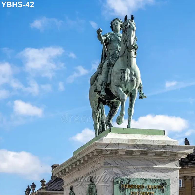 A bronze equestrian statue of a rider on a horse atop a marble pedestal, set against a clear blue sky with scattered clouds.