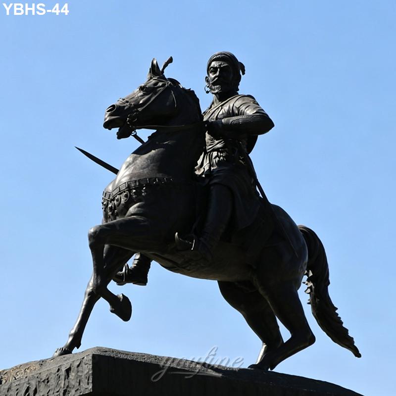 A bronze statue of a rider on horseback, holding a weapon, with intricate detail, set against a clear blue sky.