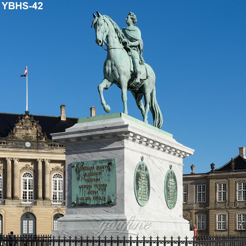 Bronze equestrian statue of a historic figure on a pedestal, set against elegant historical buildings and a clear blue sky.