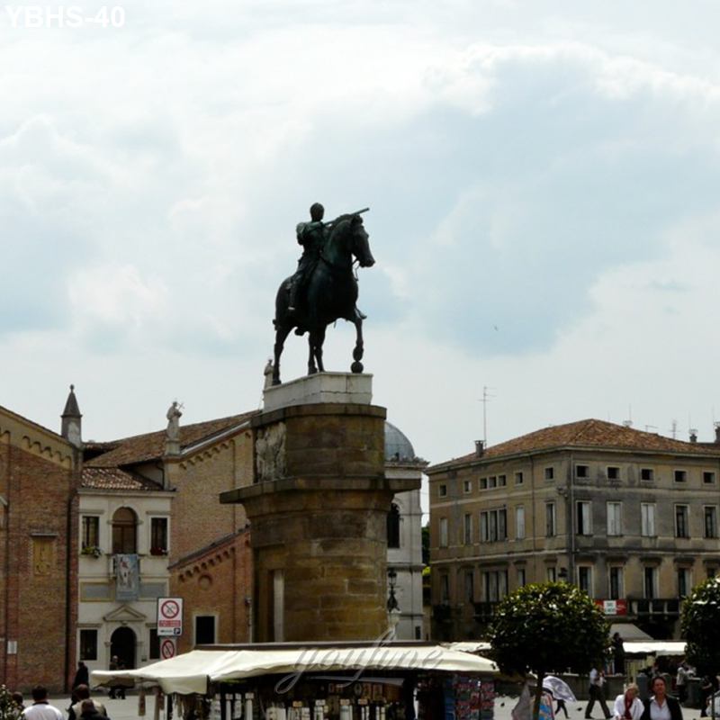 A historic equestrian bronze statue on a tall stone pedestal in a European plaza surrounded by historic buildings and market stalls.