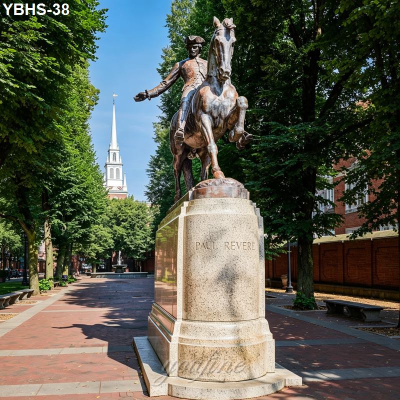 Bronze statue of Paul Revere on horseback in a shaded brick-paved historical park with a church steeple in the background.